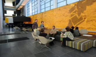 Goodyear employees in the seating area in the lobby with the large Goodyear track shoe logo on the wall