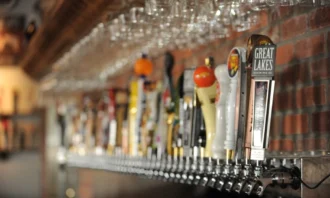 A wall of beer taps with glasses hanging above