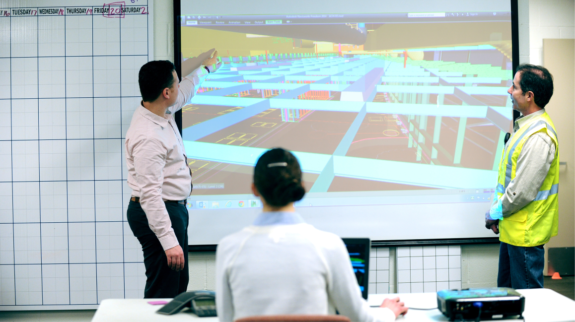 Individuals looking at CAD software on a board