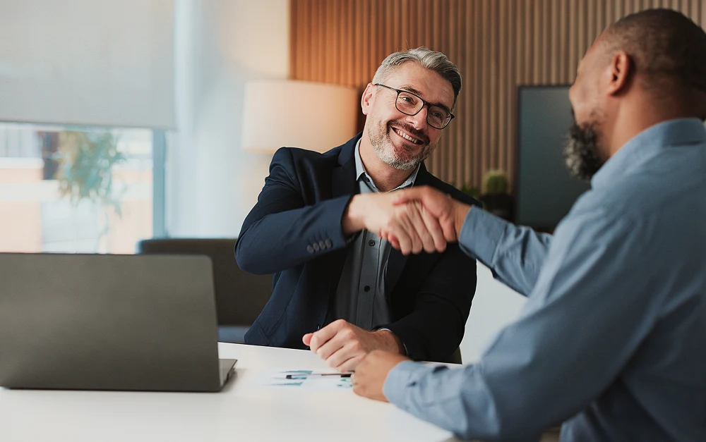 Advisor shaking hands with a client during strategic planning discussion
